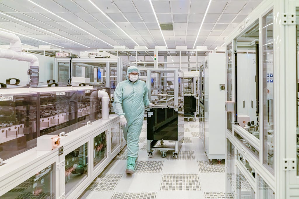 Scientist in protective gear walking in a high-tech cleanroom laboratory environment.